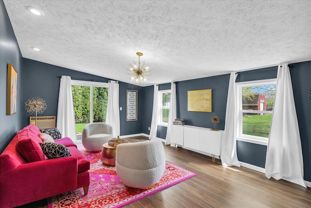 living area with lofted ceiling, a textured ceiling, baseboards, a chandelier, and wood finished floors