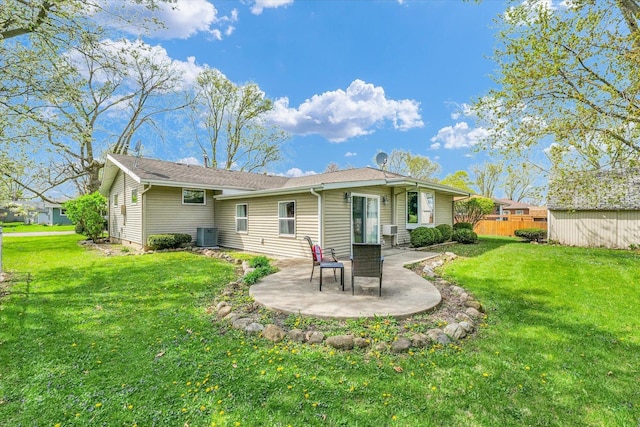 rear view of property featuring fence, a patio, central AC, and a lawn