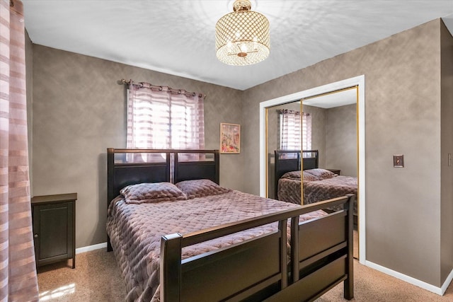 bedroom with carpet flooring, a closet, baseboards, and a notable chandelier