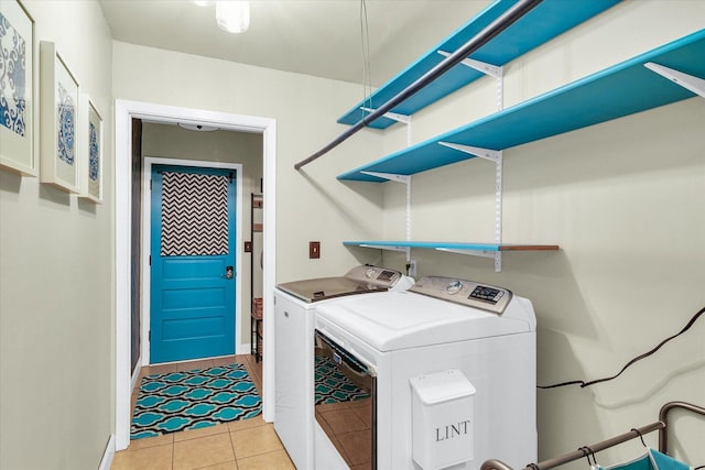 clothes washing area with separate washer and dryer, light tile patterned flooring, laundry area, and baseboards