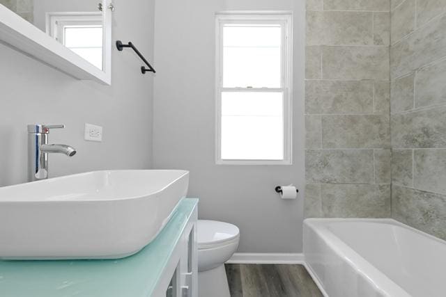 bathroom featuring toilet, vanity, baseboards, and wood finished floors