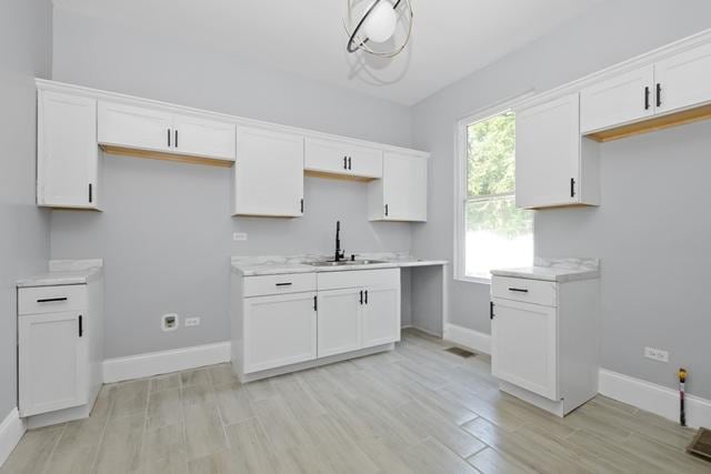 kitchen with white cabinets, light wood-style floors, and a sink