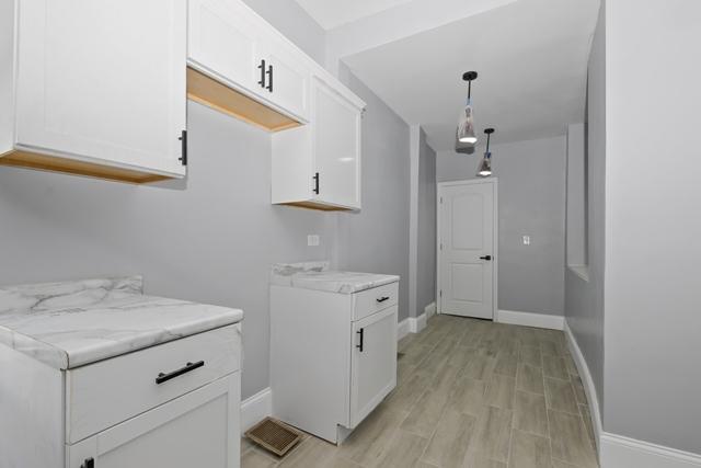clothes washing area with light wood-style flooring and baseboards