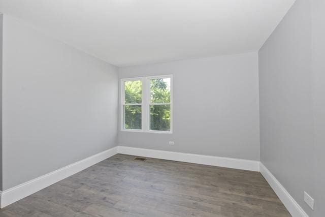 empty room with baseboards, visible vents, and wood finished floors