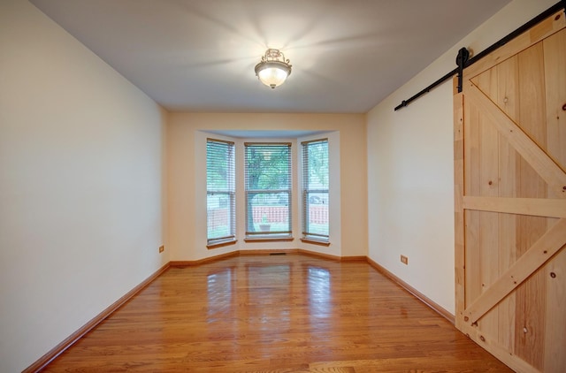 5615 Cider Grove Ct, Plainfield, IL 60586 - empty room with a barn door, light wood finished floors, and baseboards