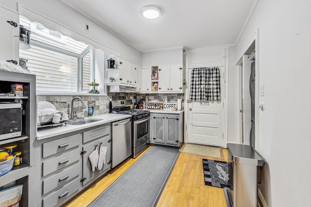 kitchen with a sink, stainless steel appliances, gray cabinets, and open shelves
