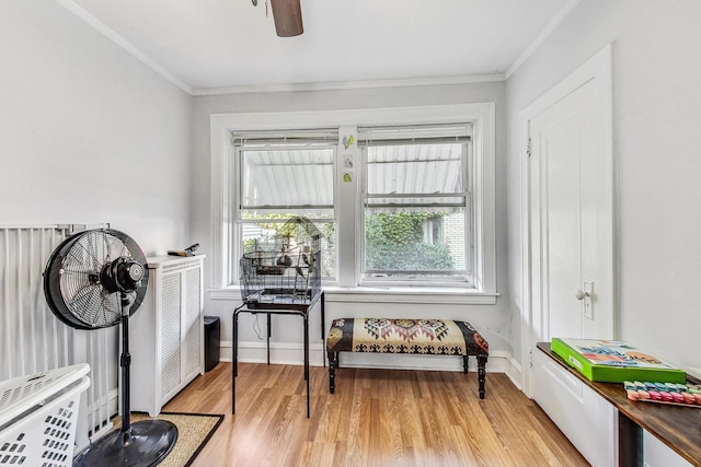 sitting room with light wood finished floors, baseboards, ornamental molding, and a ceiling fan