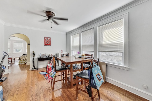 dining space with plenty of natural light, light wood-type flooring, arched walkways, and ceiling fan