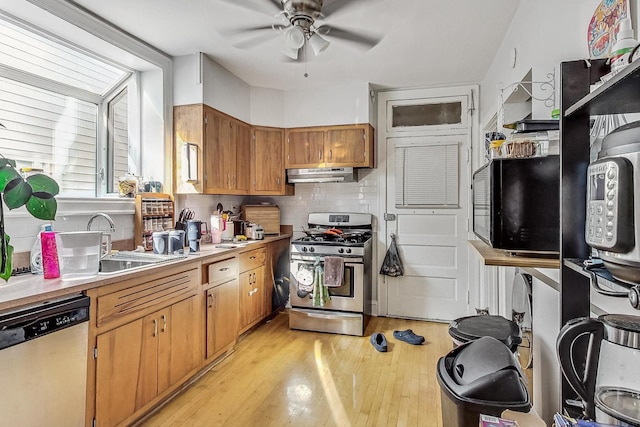 kitchen with light countertops, stainless steel appliances, under cabinet range hood, backsplash, and ceiling fan