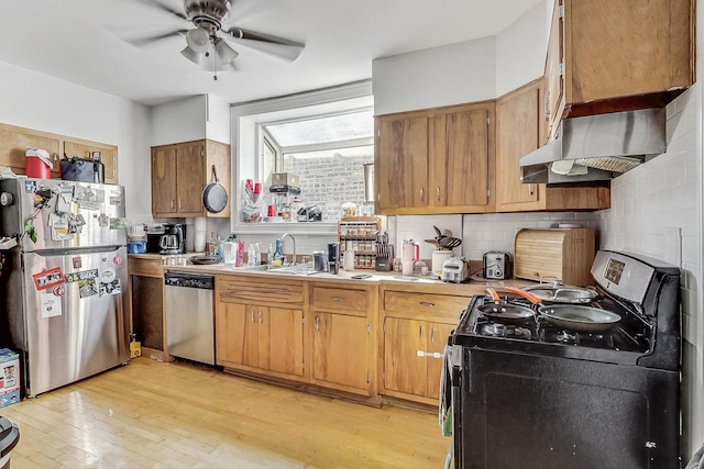 kitchen featuring light countertops, a sink, appliances with stainless steel finishes, light wood-style flooring, and decorative backsplash