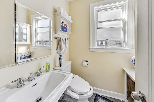 bathroom with toilet, a sink, and baseboards
