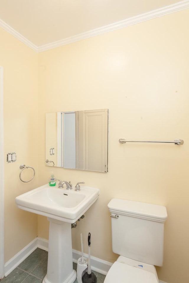 half bath featuring crown molding, toilet, a sink, tile patterned flooring, and baseboards