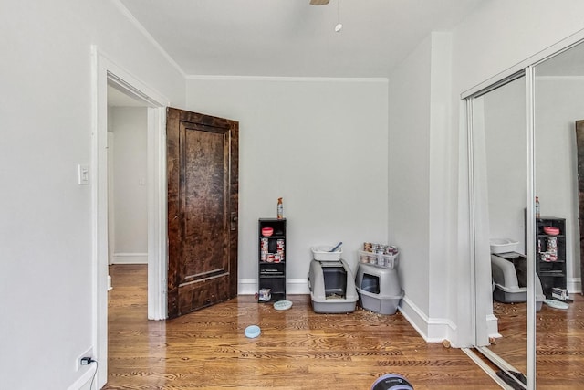 interior space featuring baseboards, crown molding, and wood finished floors