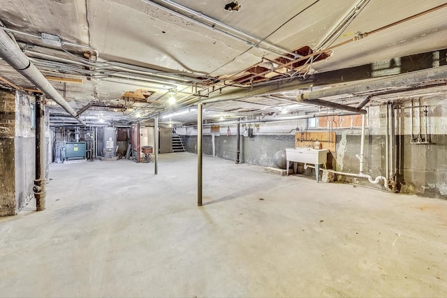 unfinished below grade area featuring water heater, stairs, and a sink