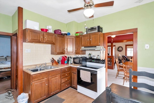 kitchen featuring ceiling fan, black microwave, electric range, ventilation hood, and a sink