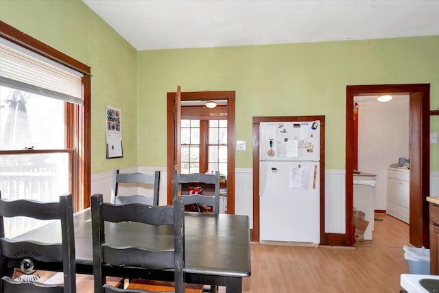dining area with washer / clothes dryer, light wood finished floors, and wainscoting