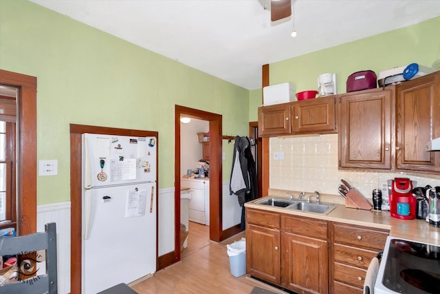 kitchen with white appliances, light wood-type flooring, tasteful backsplash, light countertops, and a sink