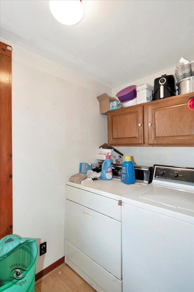 clothes washing area with washer and dryer, light wood-type flooring, baseboards, and cabinet space