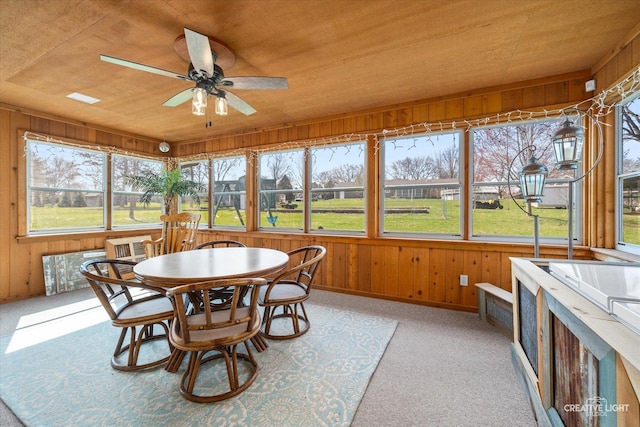 sunroom with wooden walls, wooden ceiling, and ceiling fan