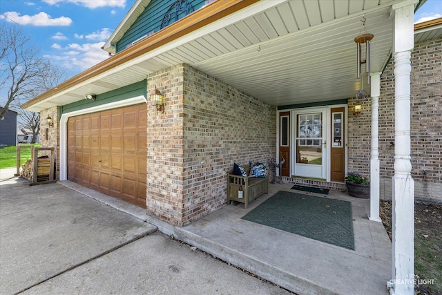 property entrance featuring brick siding, driveway, and a garage