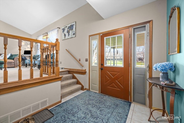 foyer with stairway, vaulted ceiling, visible vents, and light tile patterned floors