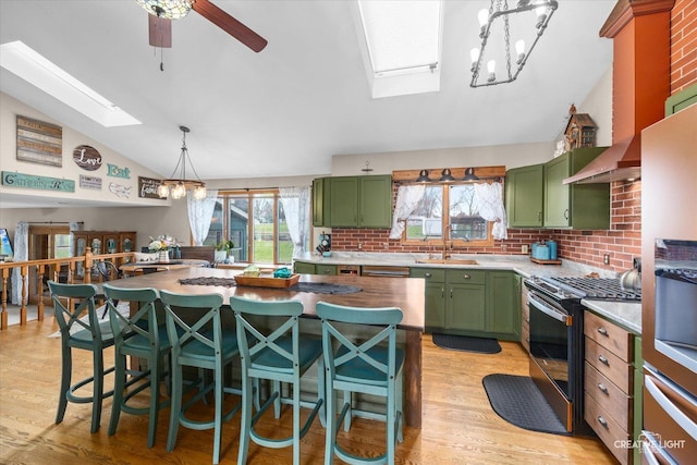 kitchen featuring stainless steel range with gas stovetop, a sink, lofted ceiling with skylight, decorative backsplash, and green cabinets