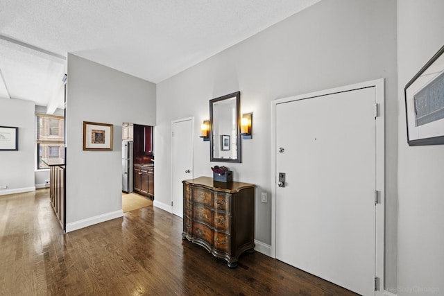 foyer featuring a textured ceiling, baseboards, and wood finished floors