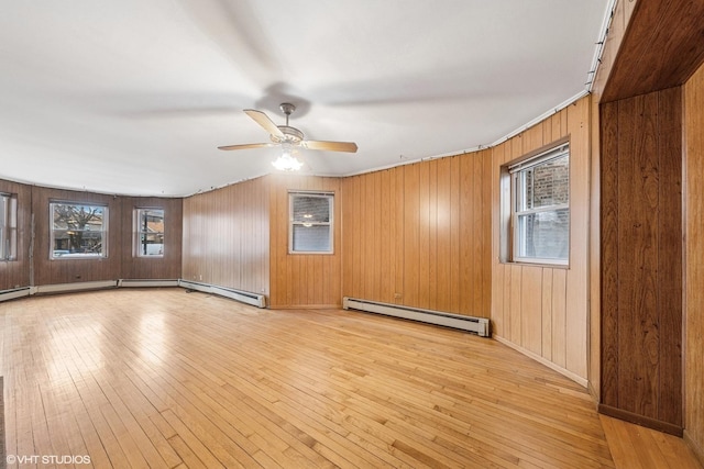 unfurnished room with a ceiling fan, a baseboard heating unit, and light wood-type flooring