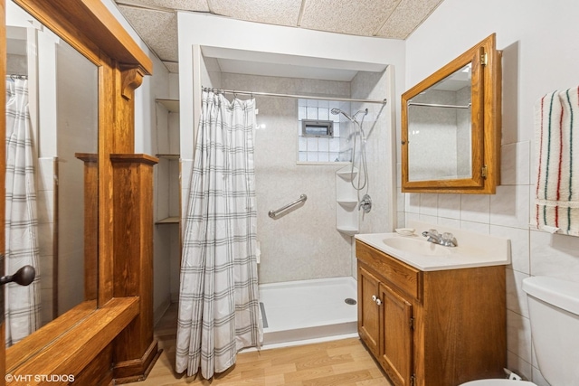 full bathroom featuring a shower with curtain, vanity, tile walls, toilet, and wood finished floors