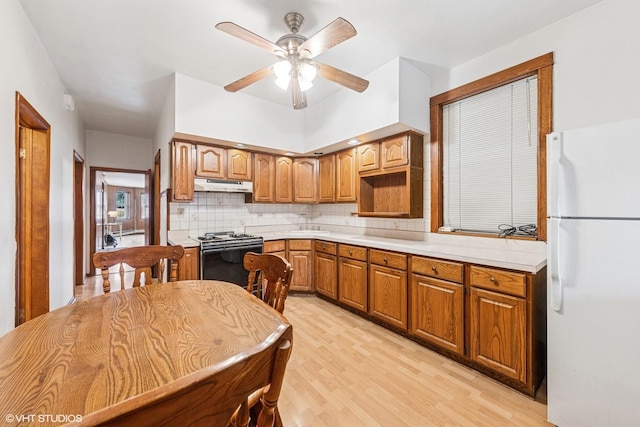 kitchen with freestanding refrigerator, tasteful backsplash, under cabinet range hood, range with gas stovetop, and ceiling fan
