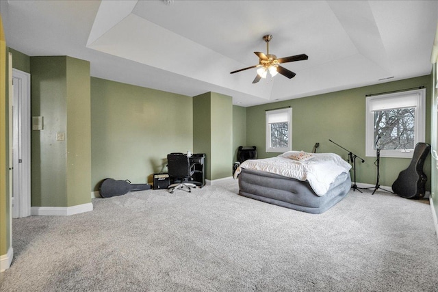 bedroom featuring baseboards, a tray ceiling, and carpet