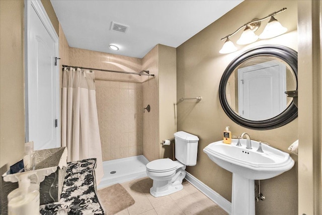 bathroom with a tile shower, tile patterned flooring, visible vents, toilet, and baseboards