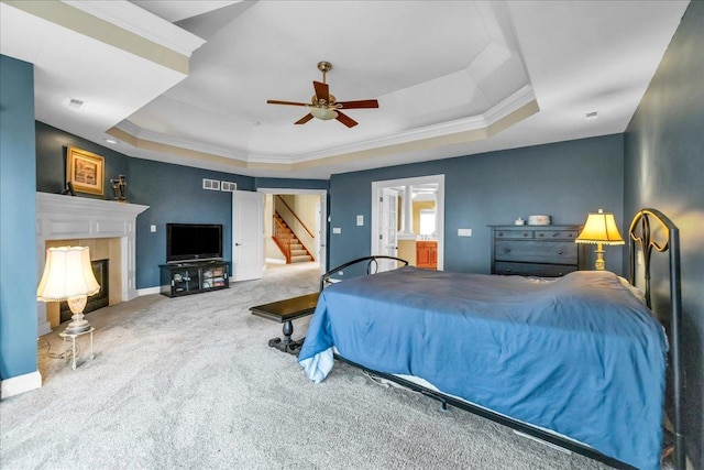carpeted bedroom with baseboards, a fireplace, a raised ceiling, and crown molding