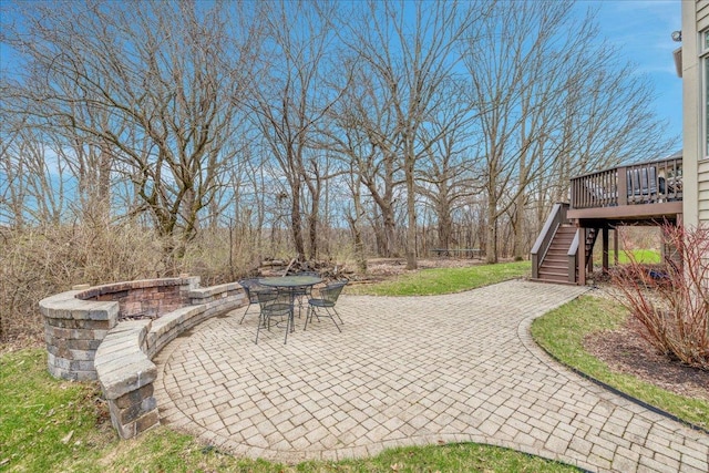 view of patio / terrace featuring stairway, a wooden deck, an outdoor fire pit, and outdoor dining space