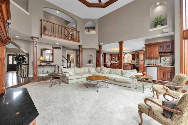 carpeted living room featuring decorative columns, a towering ceiling, and recessed lighting