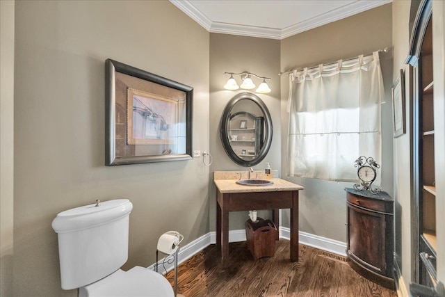 bathroom with a sink, toilet, baseboards, wood finished floors, and ornamental molding