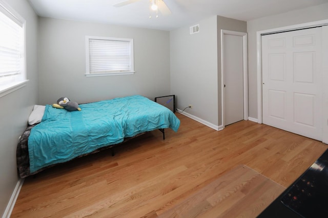bedroom with baseboards, ceiling fan, visible vents, and light wood-type flooring