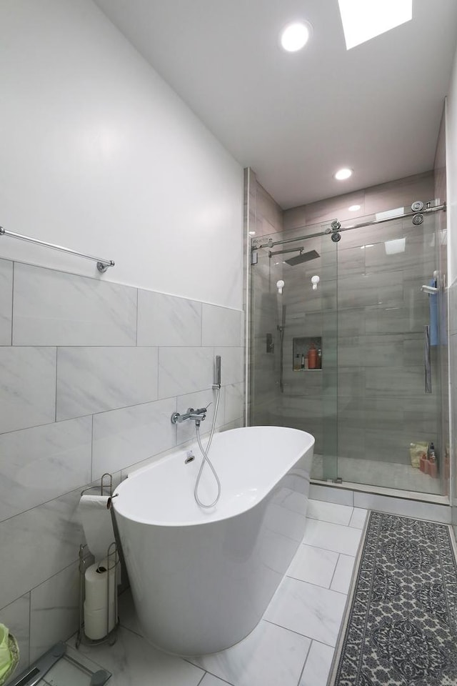 full bathroom featuring marble finish floor, recessed lighting, a soaking tub, and a shower stall