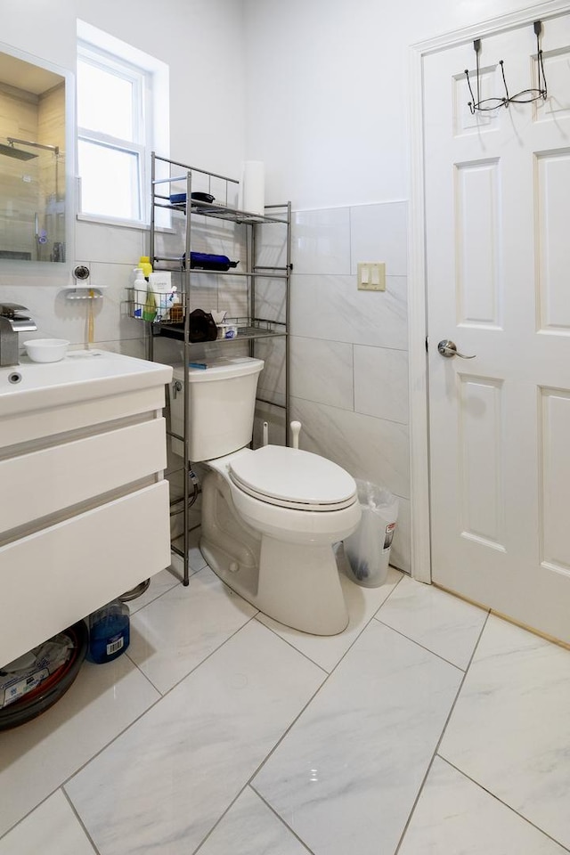 full bathroom with toilet, an enclosed shower, vanity, marble finish floor, and tile walls