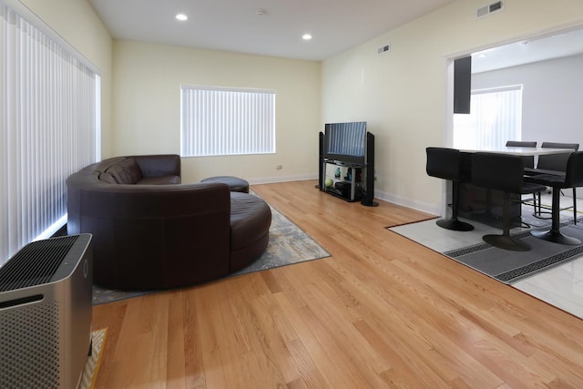 living room featuring baseboards, visible vents, recessed lighting, and light wood finished floors