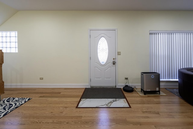 foyer featuring baseboards, lofted ceiling, and wood finished floors