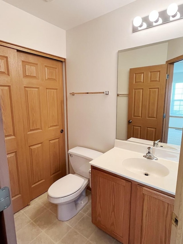 half bath with toilet, tile patterned flooring, and vanity