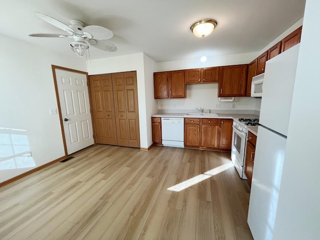 kitchen featuring light countertops, white appliances, a ceiling fan, a sink, and light wood-type flooring