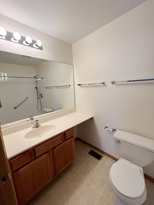bathroom featuring toilet, vanity, walk in shower, and visible vents