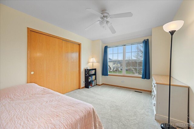 bedroom with ceiling fan, a closet, light colored carpet, visible vents, and baseboards