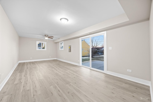 spare room featuring baseboards, plenty of natural light, a ceiling fan, and light wood finished floors
