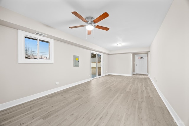 spare room featuring electric panel, light wood-type flooring, baseboards, visible vents, and ceiling fan