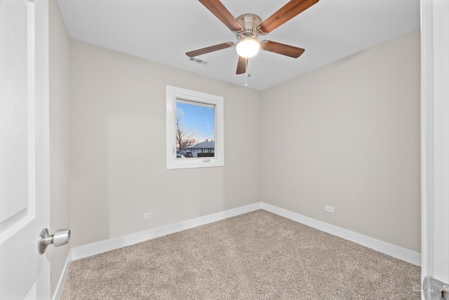 carpeted empty room with baseboards, visible vents, and a ceiling fan