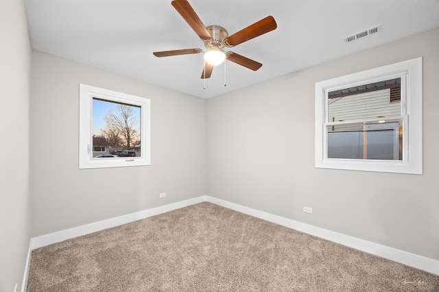 carpeted empty room with baseboards, ceiling fan, and visible vents
