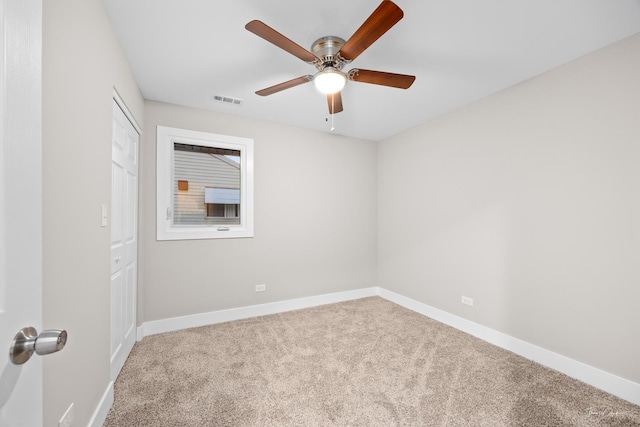 carpeted spare room featuring baseboards, visible vents, and a ceiling fan